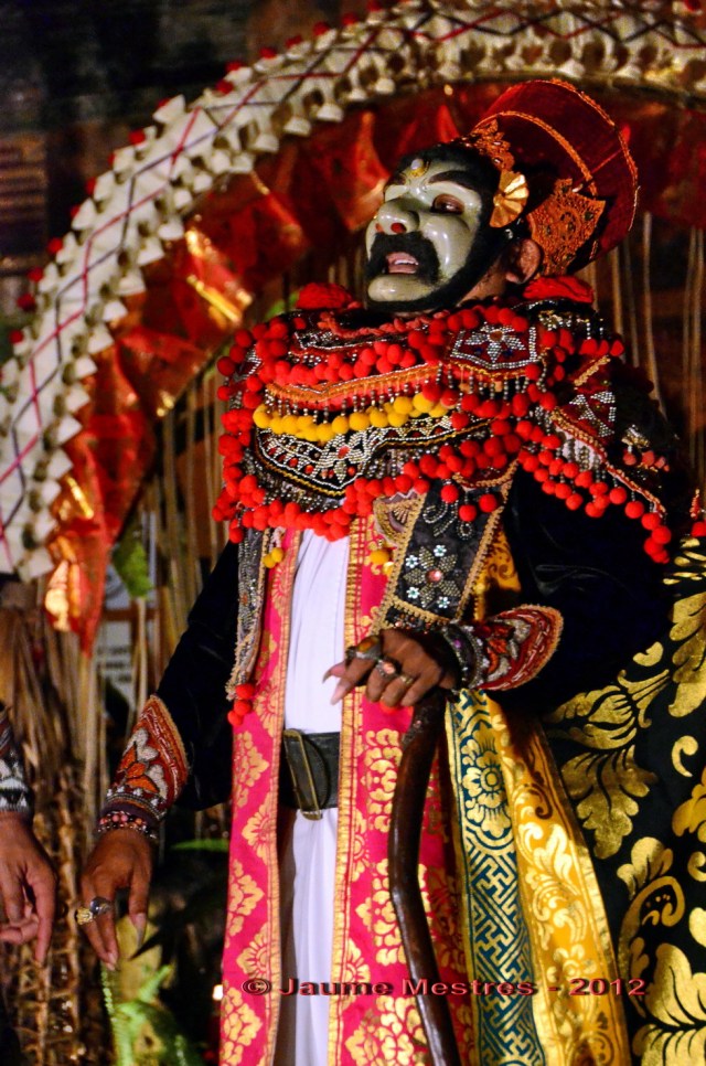 Dansa amb màscara, o topeng, al pati de palau durant la primera nit de les celebracions del funeral de Pak Cokorda Putra Dharma Yudha, membre de la família reial d'Ubud, traspassat el dia 7 de juliol. El seu cos serà incinerat demà passat, el dia 28. En una cremació que sens dubte serà multitudinària.